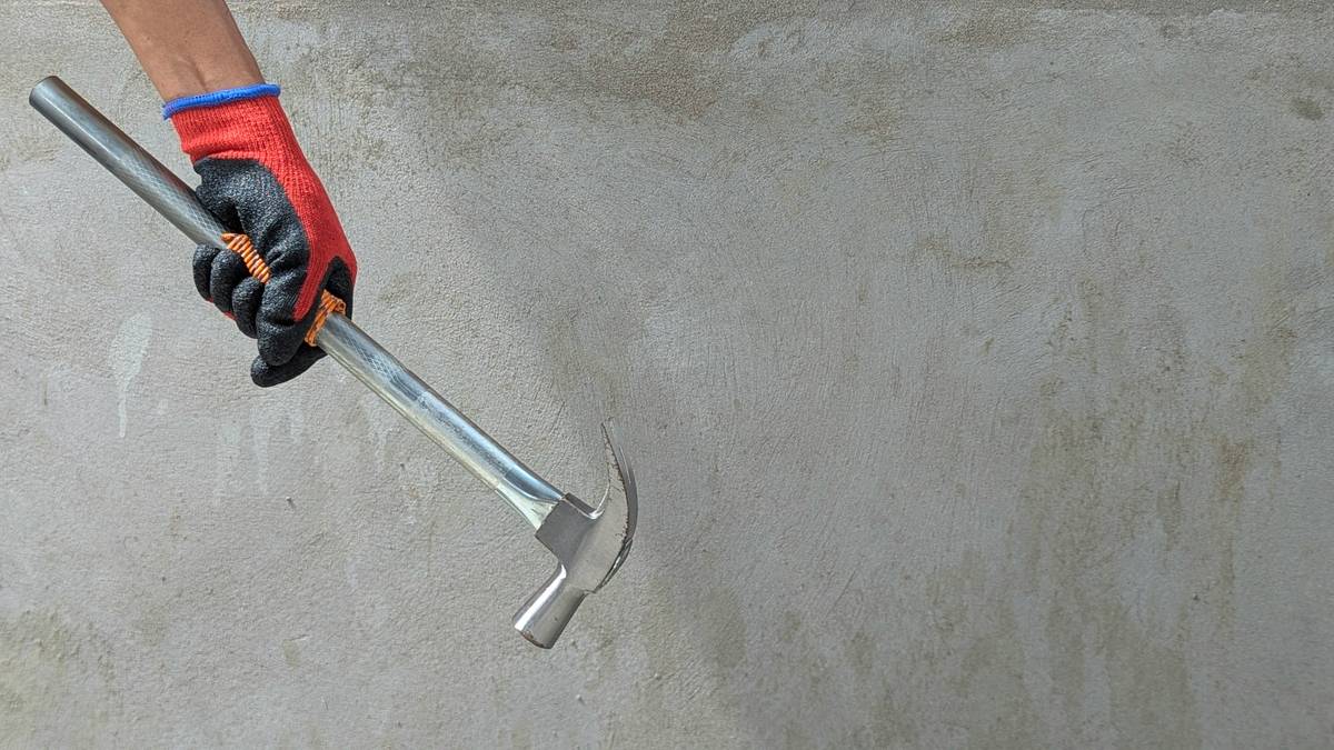 Carpenter wearing safety goggles while demonstrating how to use a hammer safely on a wooden board